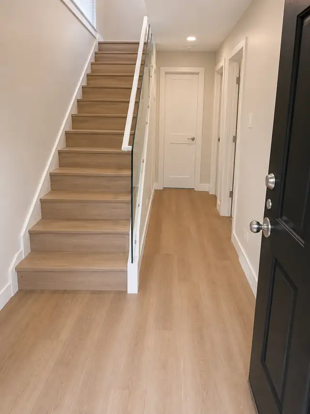 Whole-home remodel with new wood-look LVP flooring on the stairs and hallway, white trim and painted walls