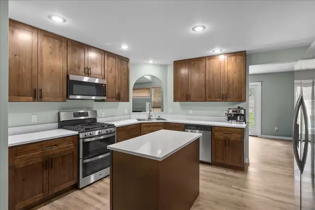 Washington kitchen remodel with stained wood cabinets, white quartz counters, center island and stainless appliances