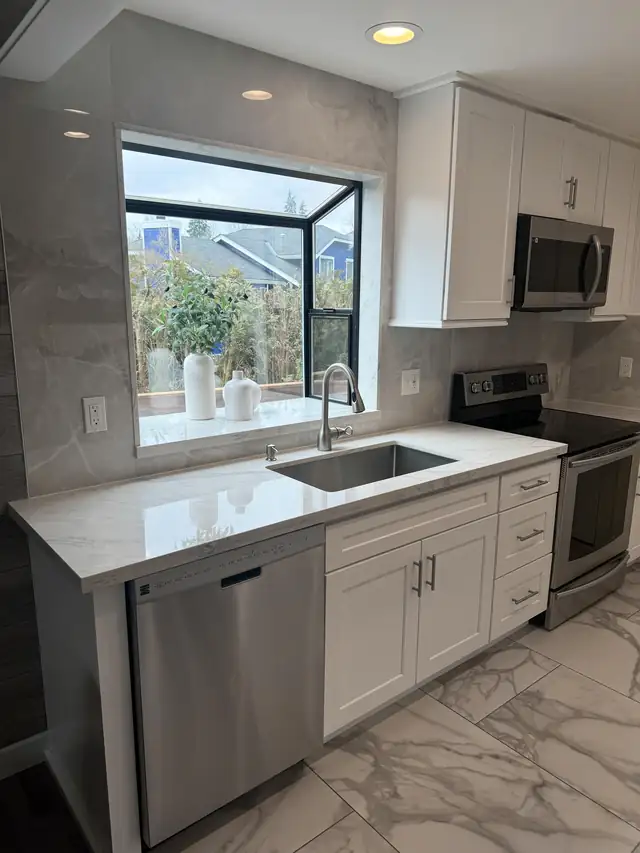 White shaker kitchen with marble-look porcelain backsplash, quartz counter and corner garden window