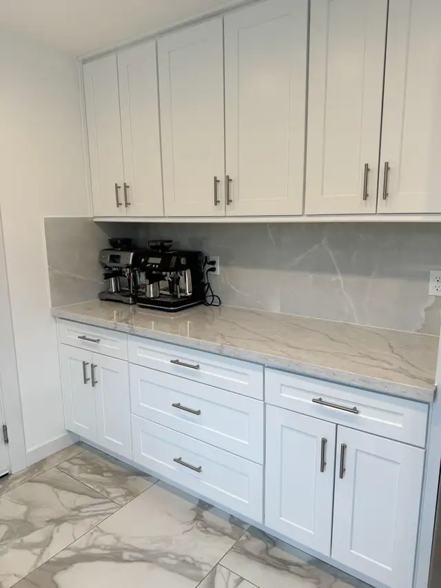 White shaker cabinets with a marble-look quartz counter and full-height backsplash set up as a coffee station
