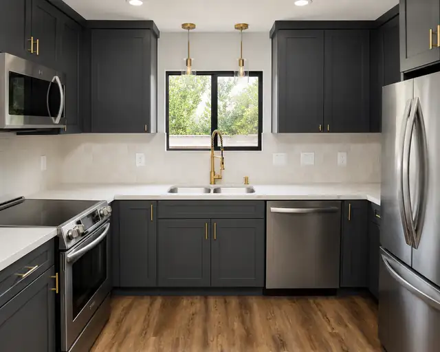 Kitchen remodel with charcoal shaker cabinets, brass pendant lights and faucet, white quartz counters and wood-look LVP flooring